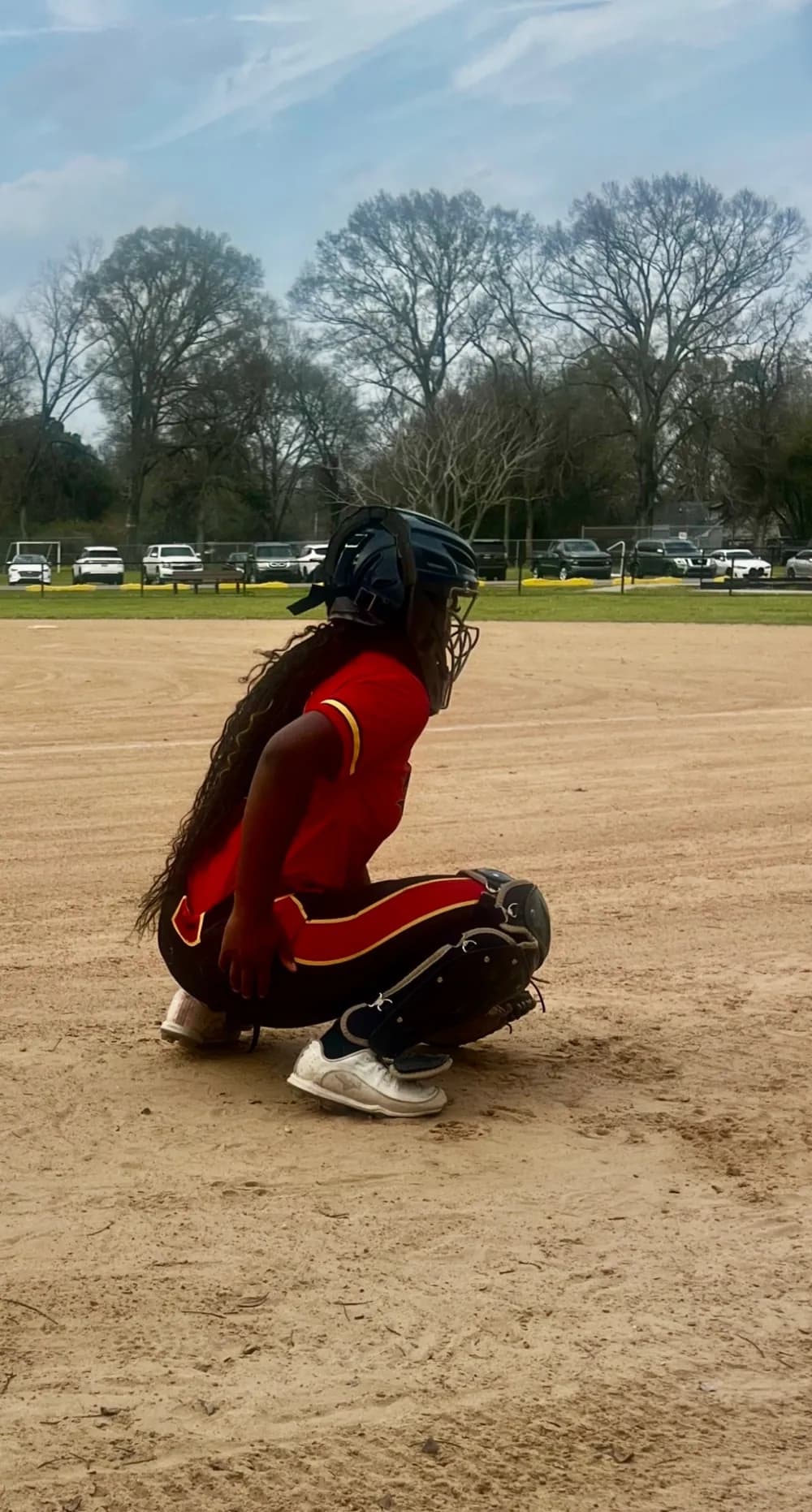 Kennedi Fair, Class of 2028 catcher, crouched in full gear in her stance behind the plate